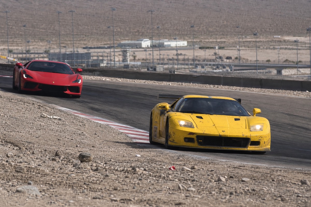 Stock car on the banked oval beside a supercar on the Las Vegas road course
