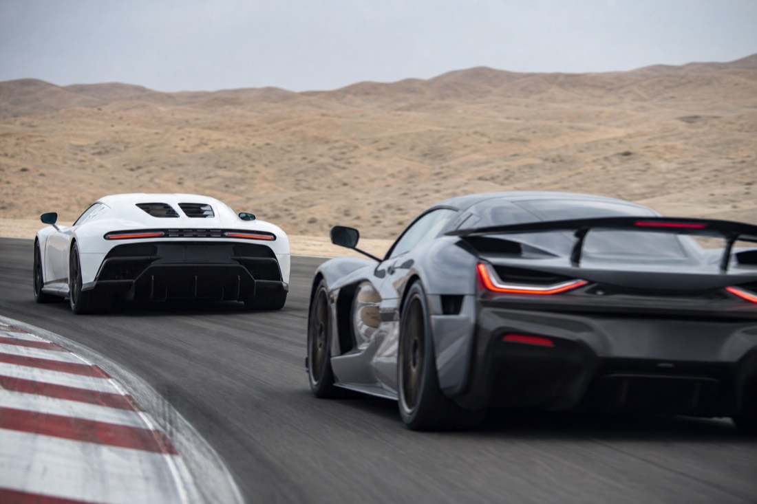 Two exotic supercars cornering on a racetrack, one chasing the other